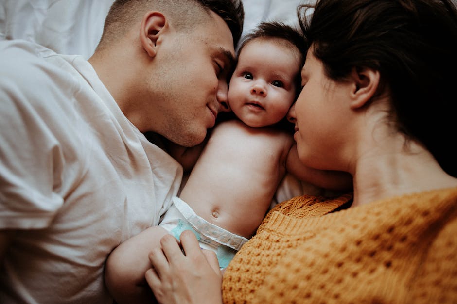 A loving family bonding moment with a newborn baby lying between parents indoors.